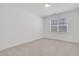 Minimalist bedroom with neutral carpet, a window with blinds, and white trim at 6680 Benchwood Path, Cumming, GA 30028