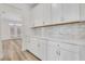 Butler pantry showcasing white cabinets, marble countertops, and tile backsplash at 6680 Benchwood Path, Cumming, GA 30028