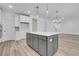 Bright kitchen features gray island with white countertop, modern pendant lights, and wood flooring at 6680 Benchwood Path, Cumming, GA 30028