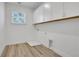 Laundry room with light wood flooring and bright white walls and cabinetry at 6680 Benchwood Path, Cumming, GA 30028