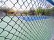 Close up of fenced in outdoor tennis court with vibrant green and blue surface and visible landscaping at 7675 Lanier View Rdg, Cumming, GA 30041