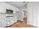 Modern kitchen with white cabinets, stainless steel microwave, and hardwood floors, next to a closet at 3317 Ridgemill Cir, Dacula, GA 30019