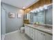 Bathroom featuring dual sinks, granite countertops, decorative lighting, and wood paneling at 1004 Westminister Ct, Woodstock, GA 30188