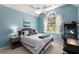 Comfortable blue bedroom featuring a large window, a ceiling fan and a well-lit space creating a calm atmosphere at 202 Carrington Estates Ct, Woodstock, GA 30188