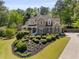 Charming brick home featuring lush landscaping, a covered porch, and classic architectural details at 202 Carrington Estates Ct, Woodstock, GA 30188