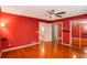 Red bedroom with hardwood floors, a ceiling fan, sliding door closets and an ensuite bathroom at 484 Aberdeen Dr, Stonecrest, GA 30083