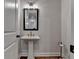Elegant powder room featuring a pedestal sink, decorative mirror, stylish fixtures, and wood floors at 3003 Evanshire Ave, Duluth, GA 30096