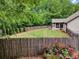 A fenced backyard with green lawn, rose bushes, and a screened porch at 3215 Trowbridge Dr, Cumming, GA 30040