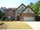 Charming two-story brick home with stone accents and a well-manicured lawn on a sunny day at 3215 Trowbridge Dr, Cumming, GA 30040