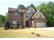 Charming two-story brick home with stone accents and a well-manicured lawn in a suburban setting at 3215 Trowbridge Dr, Cumming, GA 30040