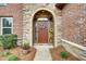 Close-up of a decorative front door with stone archway and seasonal floral arrangements at 3215 Trowbridge Dr, Cumming, GA 30040