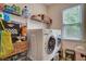 Bright laundry room featuring modern washer and dryer, storage shelves, and a window for natural light at 3215 Trowbridge Dr, Cumming, GA 30040