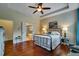 Bright main bedroom featuring hardwood floors, neutral walls, tray ceilings, and double doors to the ensuite bathroom at 3215 Trowbridge Dr, Cumming, GA 30040
