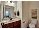 Charming powder room with granite countertop, wood cabinets, toilet, and decorative accents at 3215 Trowbridge Dr, Cumming, GA 30040