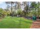 Expansive backyard with lush green grass, mature trees, playground, and storage shed at 1834 Kimberly Sw Dr, Marietta, GA 30008