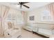 Bright Bedroom featuring two cribs, a comfortable chair, a ceiling fan and window shutters at 1834 Kimberly Sw Dr, Marietta, GA 30008