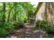 Exterior shot of a home nestled among lush greenery featuring a stone fireplace and adjacent pathway at 4030 Muirfield Ln, Marietta, GA 30068