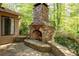 Stone outdoor fireplace and patio area surrounded by lush greenery at 4030 Muirfield Ln, Marietta, GA 30068