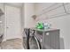 Modern laundry room features gray tile floor and new stainless steel washer and dryer set with overhead shelving at 3220 Montebello Pkwy, Cumming, GA 30028