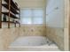 A luxurious soaking tub is beautifully tiled and set under a window with a view, complemented by open shelving for storage at 728 Wesley Nw Dr, Atlanta, GA 30305