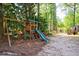 Lush backyard features a playset with slide and swing surrounded by tall trees at 728 Wesley Nw Dr, Atlanta, GA 30305