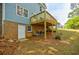 Backyard with the house showing its brick foundation, walkout door, and wooden deck at 1697 Ramblewood Way, Snellville, GA 30078
