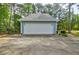Detached two-car garage with a white door and extended driveway with a backyard view at 1697 Ramblewood Way, Snellville, GA 30078