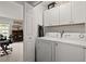Bright laundry room with white cabinets, modern washer and dryer, and an adjacent study room at 3065 Camden Way, Alpharetta, GA 30005