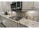 Granite countertop with cooktop and backsplash in a kitchen with stainless appliances and custom cabinets at 408 Cottonwood Cir, Peachtree City, GA 30269