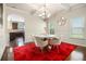 Elegant dining room featuring a round table, modern chandelier, and a striking red rug for a sophisticated ambiance at 640 Parkside Place Dr, Mcdonough, GA 30253