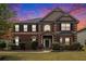Charming two-story brick home featuring manicured landscaping and a welcoming front porch under a sunset sky at 640 Parkside Place Dr, Mcdonough, GA 30253