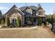 Beautiful stone home features a manicured lawn and mature evergreens highlighting the architectural details at 12640 Hearthstone Way, Alpharetta, GA 30009