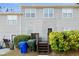 The back exterior of the townhome with stairs leading to the deck, a small lawn, and green shrubbery at 241 Odyssey Turn Nw, Conyers, GA 30012