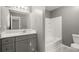 Bathroom with a gray vanity, sink, toilet, and white-tiled tub at 241 Odyssey Turn Nw, Conyers, GA 30012
