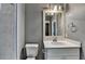 Modern bathroom with tiled walls, vanity, and sink with chrome hardware and a decorative mirror at 7160 Round Rd, Cumming, GA 30040