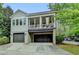 Two-story home with a three-car garage featuring an upstairs porch with white curtains at 7160 Round Rd, Cumming, GA 30040