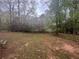 Lawn of a wooded backyard and a glimpse of the rear of the house at 883 Greenhedge Dr, Stone Mountain, GA 30088