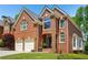 Charming two-story red brick home featuring a two-car garage and manicured lawn at 1228 Dunwoody Walk, Atlanta, GA 30338