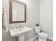 Well-lit bathroom with a classic pedestal sink, a wood-framed mirror, and a toilet at 10265 Grandview Sq, Johns Creek, GA 30097
