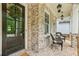 Inviting front porch with dark wood door, brickwork, and comfortable outdoor seating at 10265 Grandview Sq, Johns Creek, GA 30097