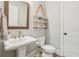 Chic powder room features a pedestal sink, a round framed mirror, and rustic rope shelving for decor at 10265 Grandview Sq, Johns Creek, GA 30097