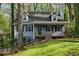 Charming two-story home featuring a cozy front porch, classic black shutters, and a well-maintained yard surrounded by lush trees at 4716 Alpine Sw Dr, Lilburn, GA 30047