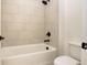 Bathroom with a bathtub and shower head is enhanced by cream colored tiled walls at 1518 Gatekeeper Ter, Marietta, GA 30066