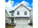 Charming two-story home featuring white siding, a front-facing garage and black trim windows under a bright, cloudy sky at 1518 Gatekeeper Ter, Marietta, GA 30066