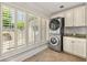 Clean laundry room featuring white cabinets, stacked washer and dryer, and ample storage at 218 Midvale Ne Dr, Atlanta, GA 30342