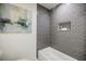 Bathroom featuring gray herringbone tile, a bathtub, recessed shelf, and modern artwork at 3154 N Druid Hills Rd, Decatur, GA 30033