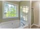 Bright bathroom featuring a soaking tub next to a large window and a glass shower at 4061 Preserve Trl, Snellville, GA 30039