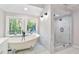 Modern bathroom with a freestanding tub, glass shower, and natural light from large windows at 100 Little Ridge Rd, Berkeley Lake, GA 30096