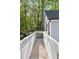 Wooden walkway with white railings connects to the main house, surrounded by lush greenery at 100 Little Ridge Rd, Berkeley Lake, GA 30096