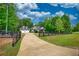 Long driveway leading to a home with an attached garage, surrounded by lush greenery and a black fence at 1080 Gaithers Rd, Mansfield, GA 30055